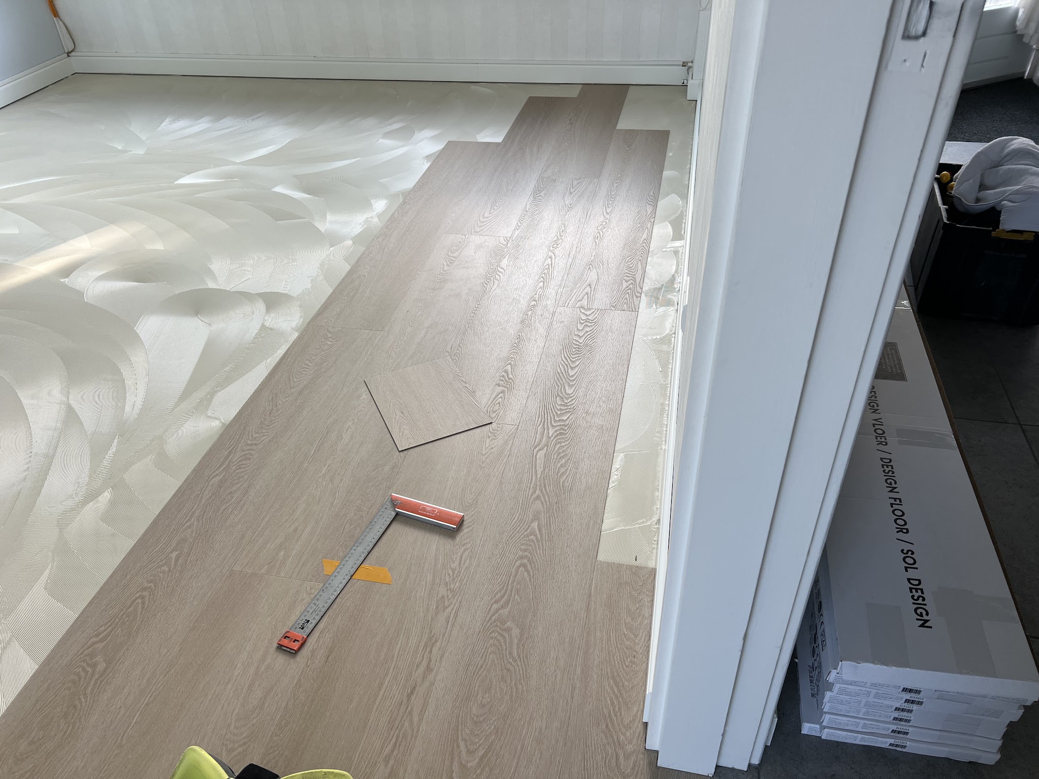 Nieuwe PVC-planken worden gelegd op een net geëgaliseerde ondervloer