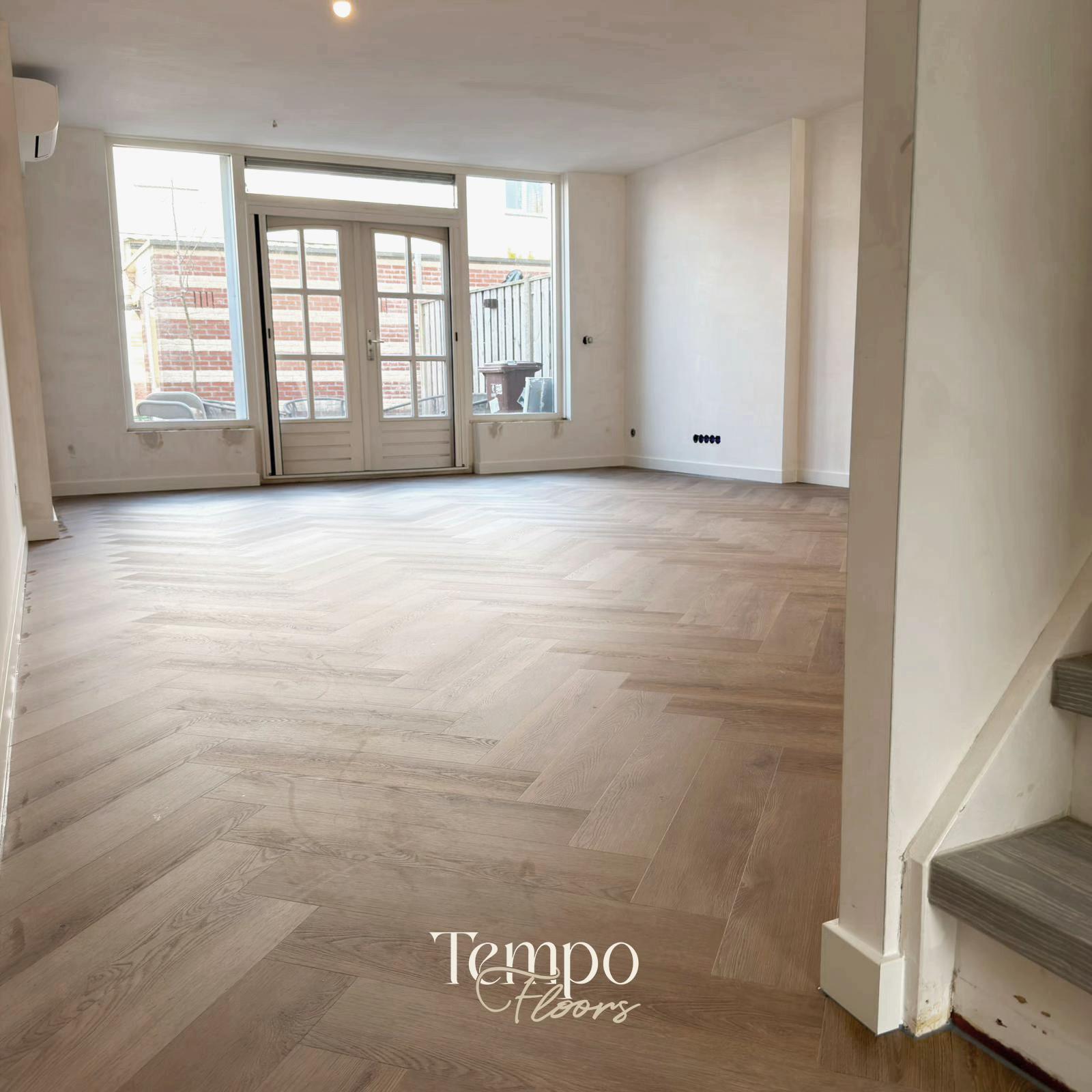 Woonkamer met lichte visgraatvloer en trap