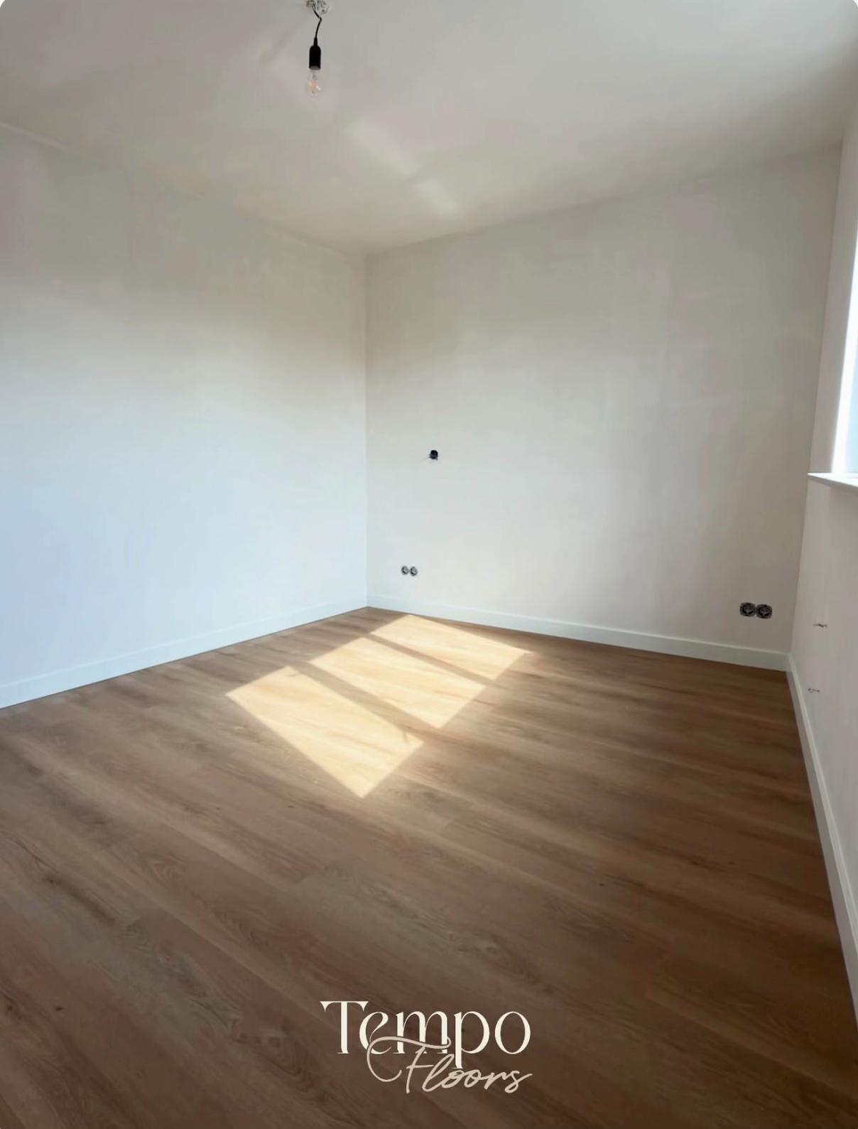 Een lege slaapkamer met zonlicht op een nieuwe PVC-vloer